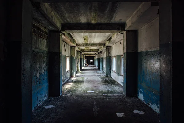 Long empty dark corridor in abandoned industrial building, perspective