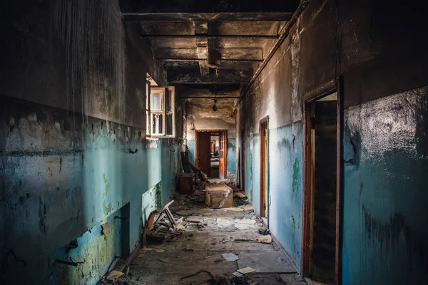 Corredor escuro vazio sujo no edifício abandonado queimado após o fogo, portas quebradas, lixo, perspectiva — Fotografia de Stock