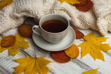 Çay beyaz rustik ahşap masa, beyaz sıcak kazak ve sarı ve turuncu rahat sonbahar sabahı arka plan, yakın bırakır