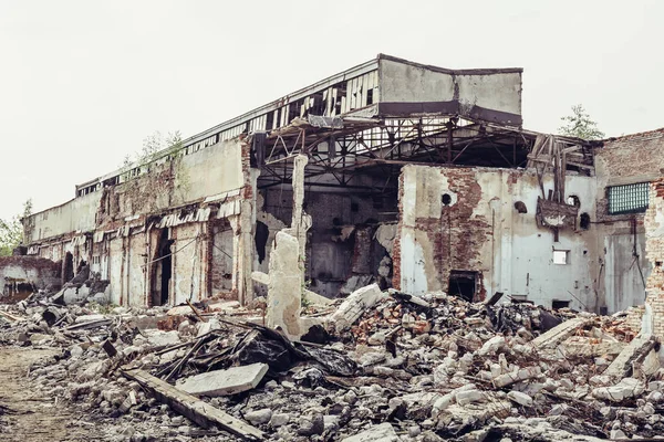 Edifício industrial abandonado arruinado com grandes pílulas de lixo de concreto, após desastre natural, furacão, terremoto ou guerra — Fotografia de Stock