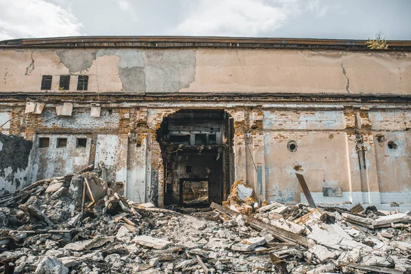 Edifício industrial abandonado arruinado com grandes pílulas de lixo de concreto, após desastre natural, furacão, terremoto ou guerra — Fotografia de Stock