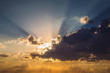 Bulutlar ve günbatımı güneş ışınlarının mavi ve turuncu gökyüzü arka plan
