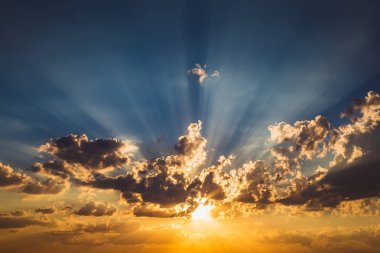 Bulutlar ve günbatımı güneş ışınlarının mavi ve turuncu gökyüzü arka plan