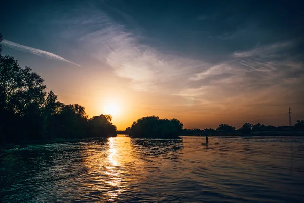 Bel tramonto drammatico sul fiume con sagome di alberi in ombre e nuvole sul cielo — Foto Stock