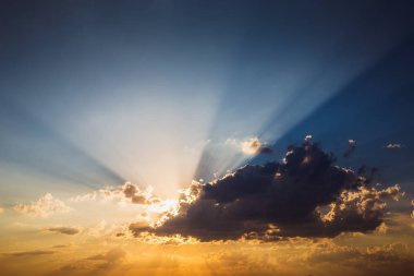 Mavi ve turuncu gökyüzü arka plan bulutlar ve dramatik günbatımı güneş ışınları ile