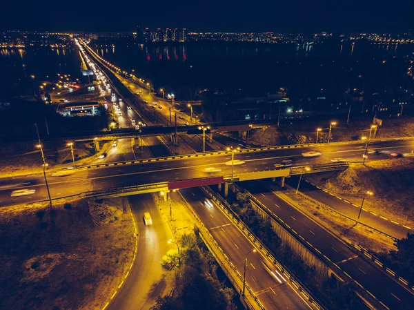 Aerial view to road junction with bridges and highways, modern city with night illumination and car traffic — Stock Photo, Image