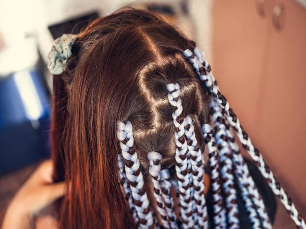 Hairdresser weaves braids with kanekalon material to young girl head, thick plaits or pigtails - African or Afro braids, close up — Stock Photo, Image