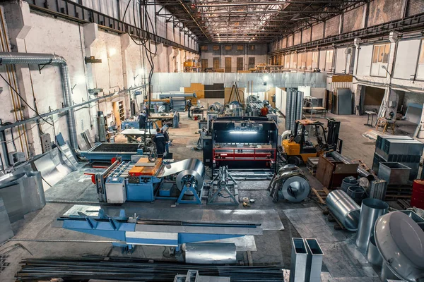 Sopa de trabajo con herramientas y equipos de maquinaria, rollos de acero galvanizado para la producción de tubos metálicos y tubos para sistemas de ventilación industrial en fábrica — Foto de Stock