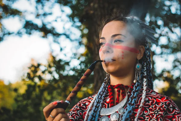 Красивая молодая девушка в платье коренных американцев курение трубки — стоковое фото