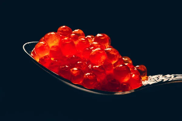 Red caviar in spoon on black background, macro photo Stock Photo