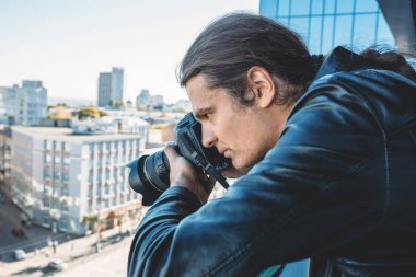 Araştırmacı veya özel dedektif ya da muhabir ya da fotoğrafta binasının balkonundan profesyonel fotoğraf makinesi ile paparazzi