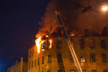Gece, alev ve duman, itfaiyeci vinç üzerinde binanın çatı evi yanan ateş ile su hortum dan söndürür