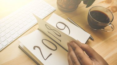 Yeni yıl 2019 önümüzdeki kavramdır. El ahşap masa üzerinde Not Defteri sayfası döndürür. 2018 dönüyor, 2019 açma