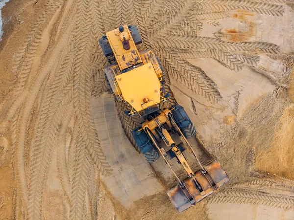 Gelber Bagger oder Planierraupe arbeitet auf Baustelle mit Sand, Luftaufnahme oder Draufsicht — Stockfoto