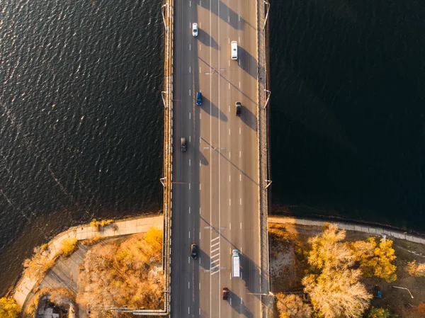 Luft- eller topudsigt fra drone af betonbro med asfaltvej eller motorvej over stor flod med bybiltrafik, bytransport - Stock-foto