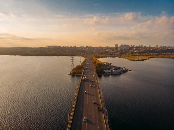 Flygfoto över bron med biltrafiken över floden, panorama vid solnedgången — Stockfoto