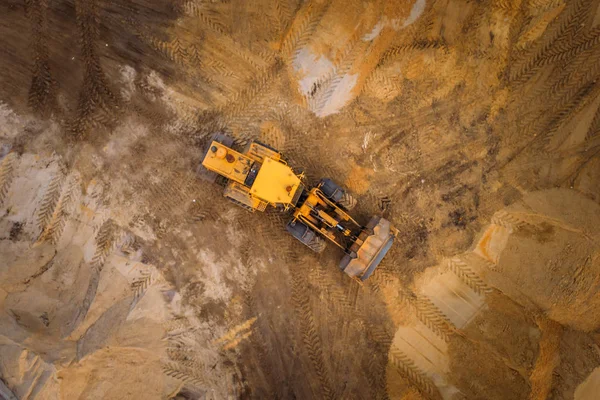 Gelber Bagger oder Planierraupe arbeitet auf Baustelle mit Sand, Luftaufnahme oder Draufsicht — Stockfoto