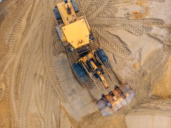 Yellow excavator or bulldozer works on construction site with sand, aerial or top view — Stock Photo, Image