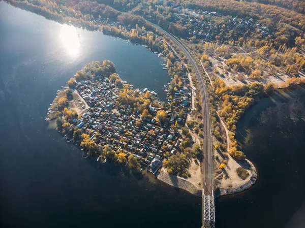 Aldeia suburbana com muitas pequenas casas perto de ferrovia e grande rio azul, vista aérea — Fotografia de Stock