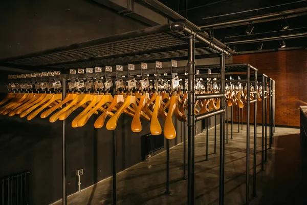 Wooden hangers with numbers in dark empty cloakroom or checkroom or wardrobe — Stock Photo, Image