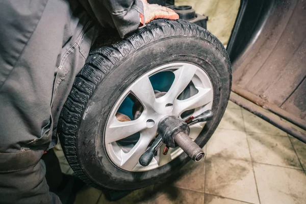 Trabajador mecánico hace equilibrio rueda de la computadora en equipo especial máquina herramienta en servicio de reparación de automóviles —  Fotos de Stock