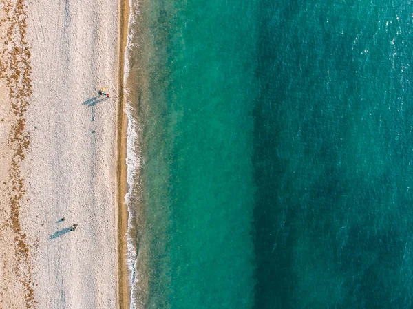 Widok z lotu ptaka z drone dzikiej plaży piaszczystej i ludzi z lazurowymi wodami i wodorostów z góry, w tle natura z miejsca kopii — Zdjęcie stockowe