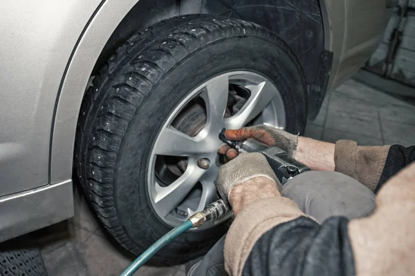 Trabalhador mecânico de automóveis fazendo substituição de pneu ou roda com chave pneumática na garagem da estação de serviço de reparação — Fotografia de Stock