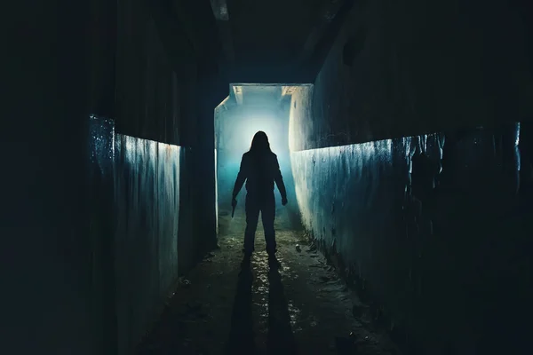 Adam manyak ya da katil ya da korku katil karanlık korkunç ve ürkütücü koridorda elinde bıçak ile silüeti. Gerilim ortamda suç soyguncusu ya da tecavüzcü kavramı