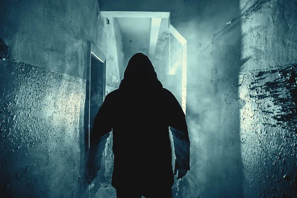 Dark silhouette of strange danger man in hood in back light with smoke or fog in scary grunge corridor or tunnel — Stock Photo, Image