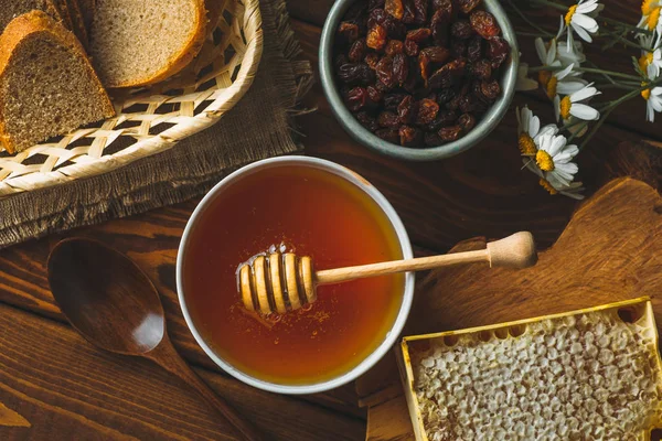 白いセラミック ボウル、蜂蜜ドリッパー スプーン、素朴な木製のテーブルに自家製ハニカム蜂蜜します。 — ストック写真