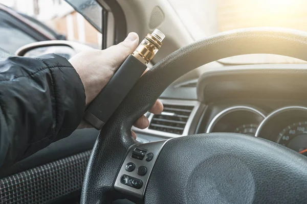 Vape device in male hand on car steering wheel — Stok Foto