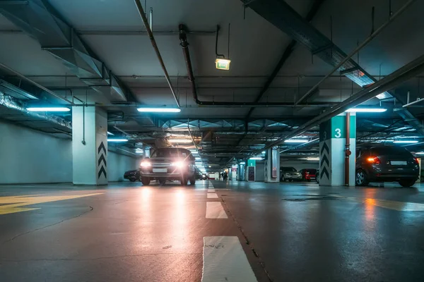 Birçok araç ve okları katta modern alışveriş merkezi altında iç aydınlatmalı Yeraltı otopark