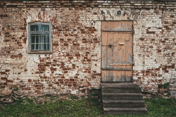 Porta fechada de madeira velha e etapas na parede antiga do edifício do tijolo — Fotografia de Stock