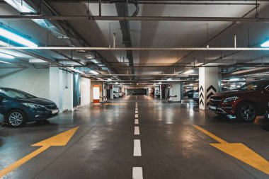 Birçok araç ve okları katta modern alışveriş merkezi altında iç aydınlatmalı Yeraltı otopark