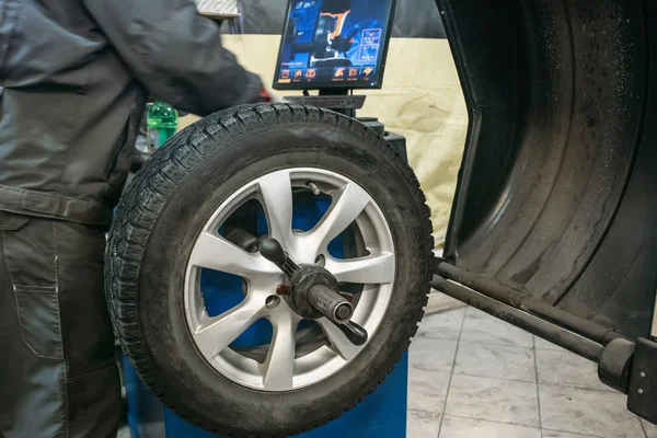 Trabalhador mecânico faz balanceamento roda de computador no equipamento especial máquina-ferramenta no serviço de reparação de automóveis — Fotografia de Stock