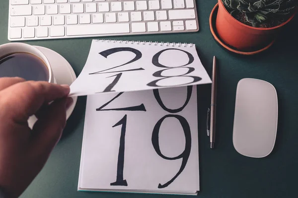 2018 está girando, 2019 está abrindo no bloco de notas pela mão masculina na mesa escura como plano de fundo abstrato do ano novo do negócio — Fotografia de Stock