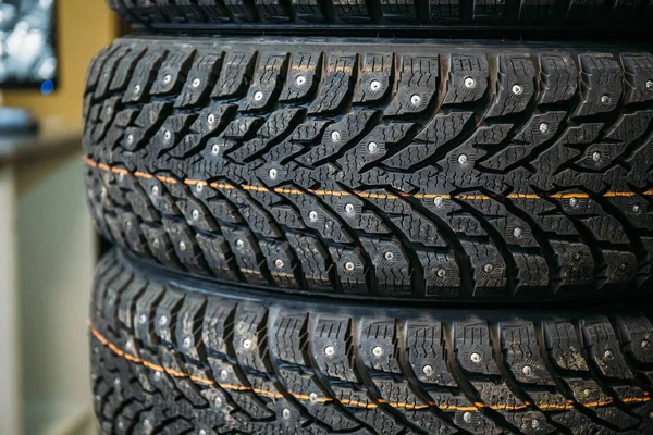 Pila de nuevo neumático tachonado de invierno con picos de metal en la tienda, ruedas de coche de goma — Foto de Stock