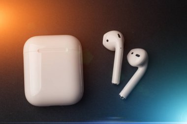 Beyaz Kablosuz bluetooth kulaklık ya da kulaklık ve depolama ve koyu arka plan üzerinde mavi ve kırmızı ışık efektleri ile şarj için beyaz kutu