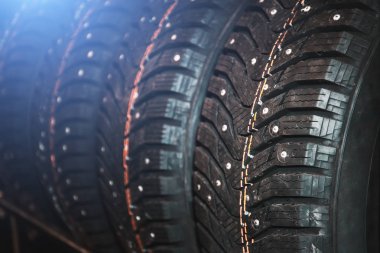 Satır yeni kış lastik deposundaki metal çiviler, otomatik araba tekerlekleri mavi ışık etkisi ile çivili