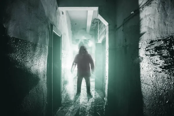 Silhouette of man maniac or killer or horror murderer with knife in hand in dark creepy and spooky corridor. Thriller atmosphere — Stock Photo, Image