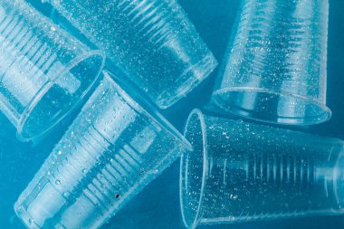 Tek kullanımlık plastik bardak damla su mavi bir arka plan üzerinde Kapat