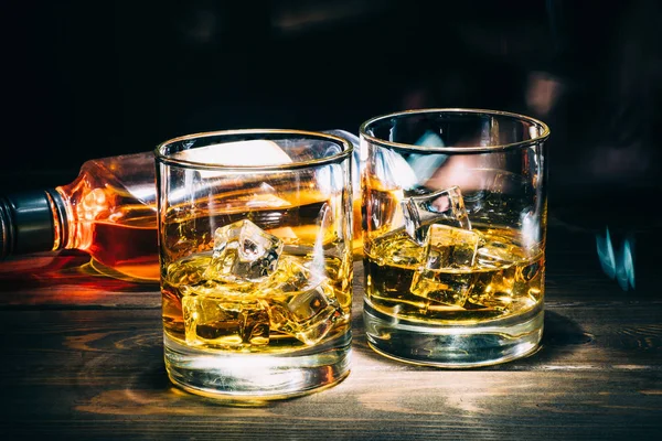 İki kadeh viski ya da buz küpleri ve koyu ahşap arka plan alkol içki şişe kanyak viski — Stok fotoğraf