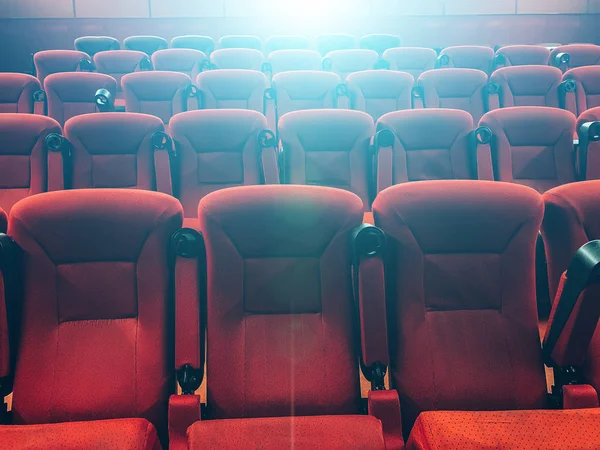 Filas vacías de sillas rojas en el cine o el teatro en la luz azul del proyector — Foto de Stock