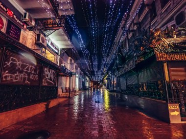 Yalta, Crimea - Şubat 2019 yaklaşık: Eski binalar, arabalar, mağaza ve gece şehir ışıkları setin yakınındaki güzel ışıklı Avrupa geniş şehir sokak asfalt yansıyan