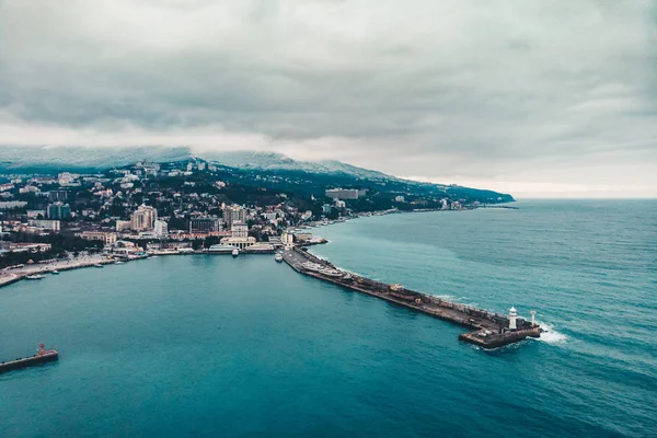 Vista aérea do dique de Yalta do drone, farol velho no cais, paisagem da costa do mar e edifícios da cidade nas montanhas, panorama bonito do inverno do recurso europeu, Crimea — Fotografia de Stock