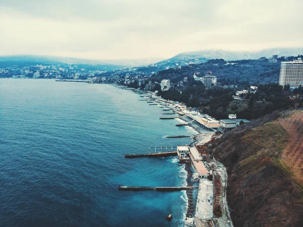 Légi panoráma a téli jaltai felhős napon, töltés a hullámtörő, régi európai város a Fekete-tenger, a hegyek, gyönyörű táj város — Stock Fotó