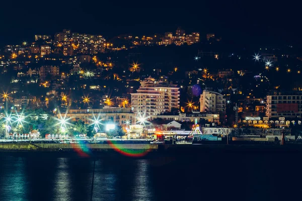 Embarque de Yalta à noite, edifícios da cidade luzes refletidas no mar negro, belo resort na Crimeia com montanhas e mar — Fotografia de Stock