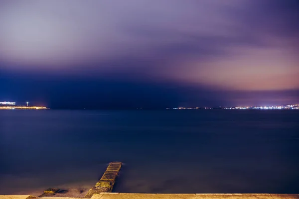 Pier concreto após o pôr do sol na água do mar, paisagem noturna com porto e oceano — Fotografia de Stock