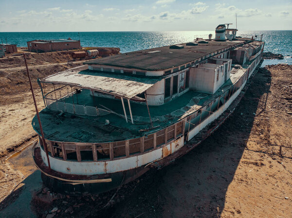 Вид с воздуха на старый заброшенный ржавый корабль на мель после кораблекрушения на побережье Крыма на песчаном пляже
