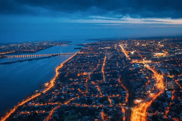 Vista aérea de la ciudad nocturna Voronezh con carreteras iluminadas, edificios, río y puente, tiro con dron — Foto de Stock